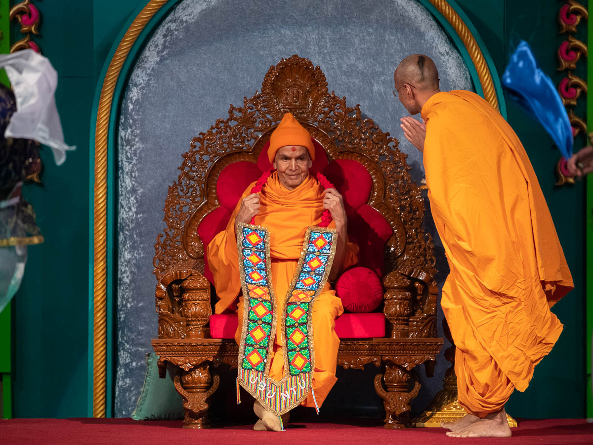 Priyavrat Swami honors Swamishri with a garland