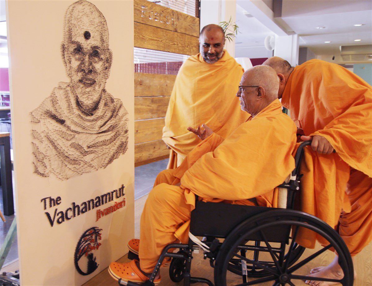 Pujya Doctor Swami engrossed in a thread portrait of Mahant Swami Maharaj, depicting the 'Jivandori' theme of the shibir