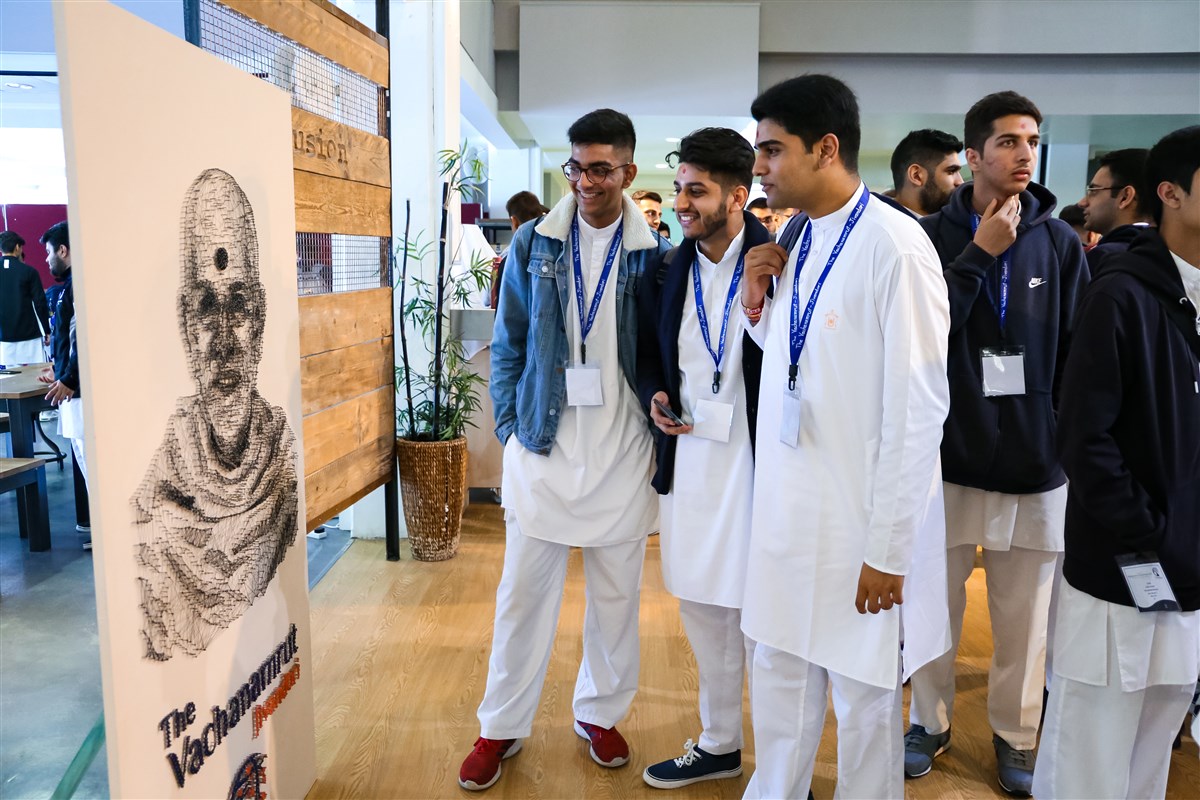 Delegates view a thread portrait of Mahant Swami Maharaj depicting the theme of the shibir