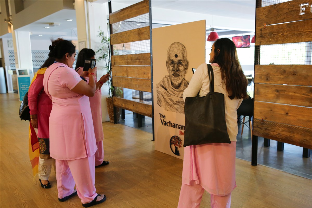 Delegates view a thread portrait of Mahant Swami Maharaj, depicting the 'Jivandori' theme of the shibir