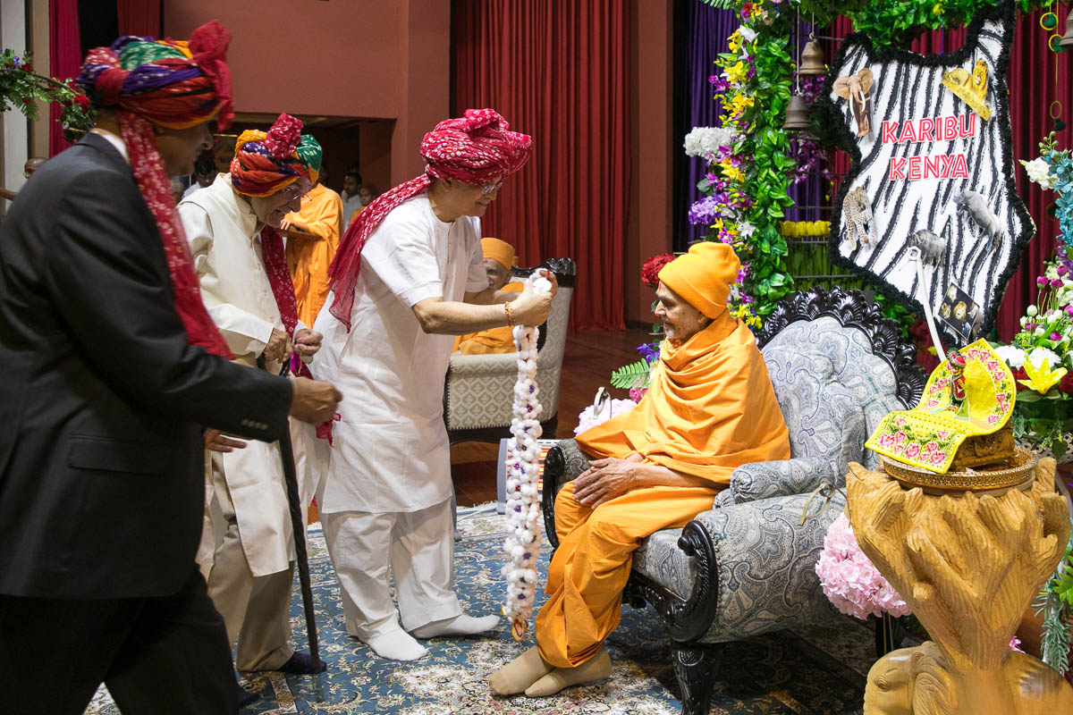 Devotees welcome Swamishri with a garland