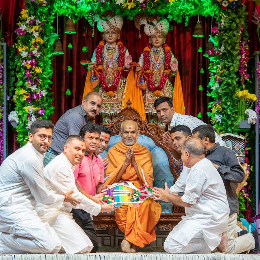 Devotees honor Swamishri with a garland