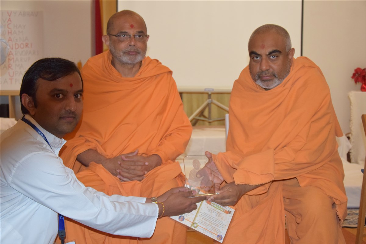 A delegate receives a prize for his outstanding Satsang Examination results