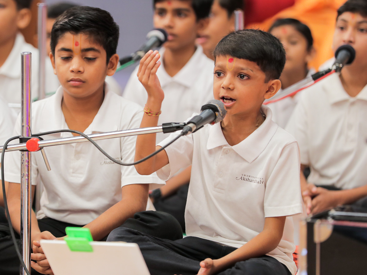 A child sings a kirtan in Swamishri's morning puja