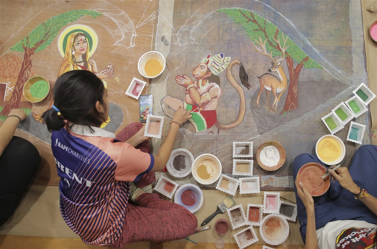 Volunteers prepare a thematic rangoli with coloured powder