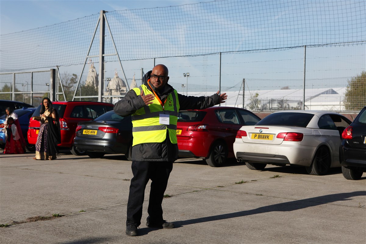 A volunteer guides cars in one of the many car parks serving visitors throughout the day