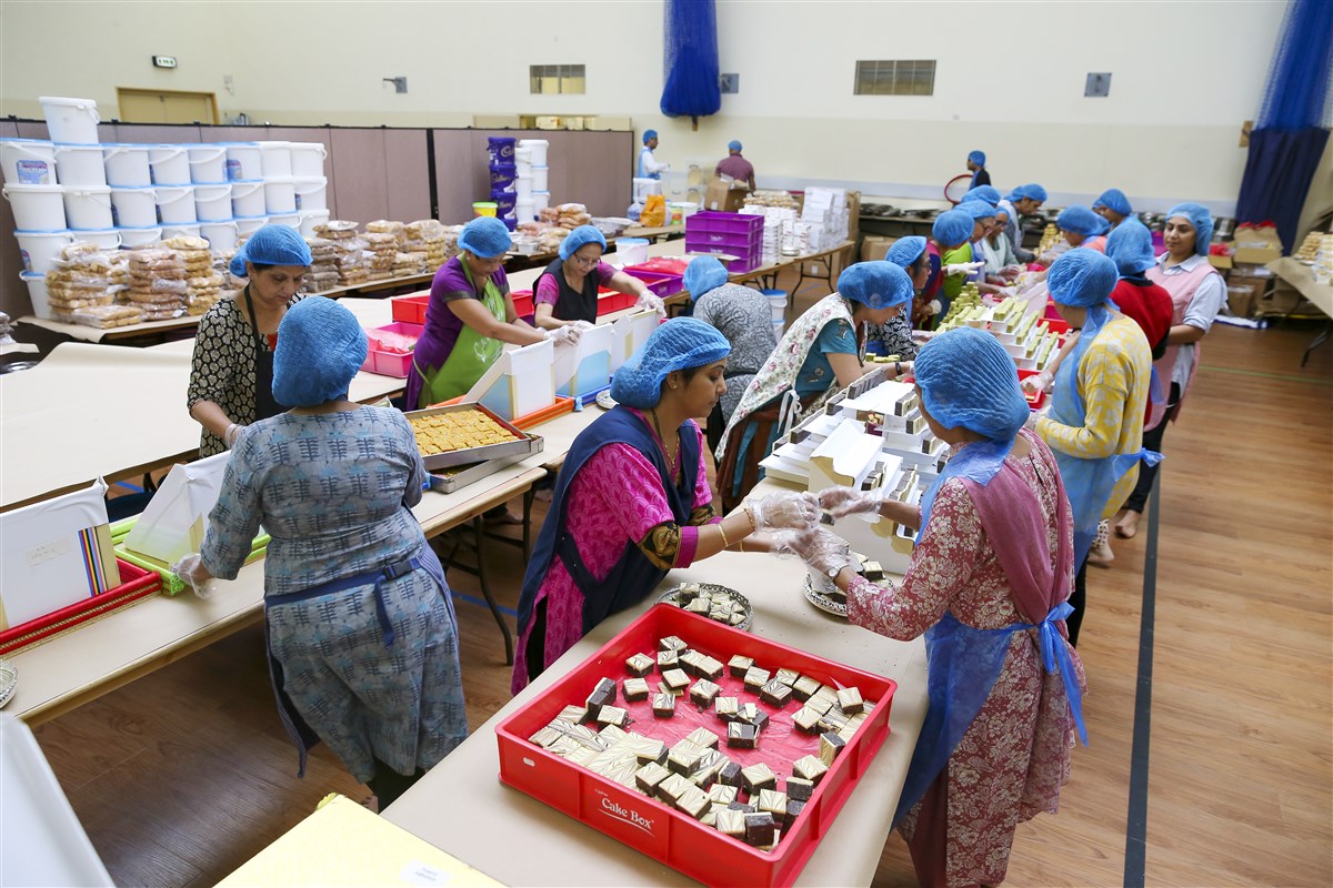 Volunteers prepare decorative plates of Indian sweets for the annakut