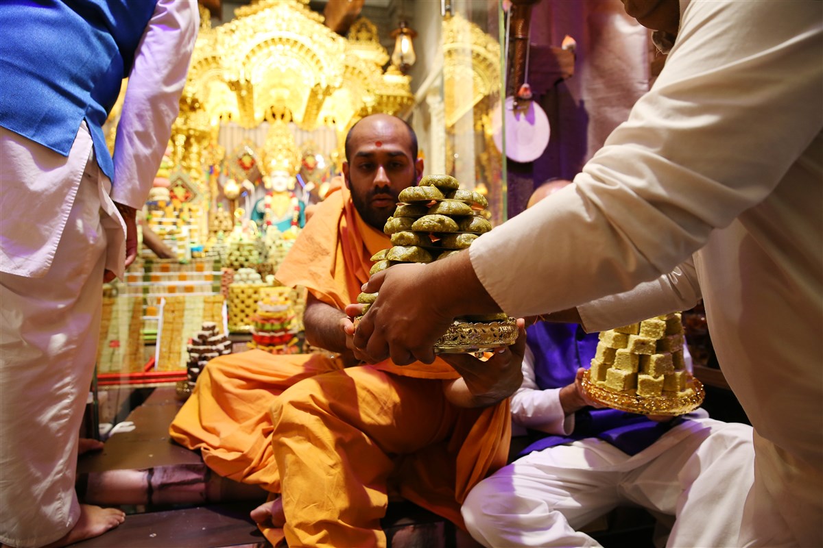 A swami helps assemble the annakut in the mandir