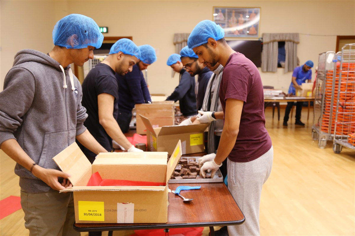 Volunteers help prepare Indian sweets for the visitors' prasad boxes