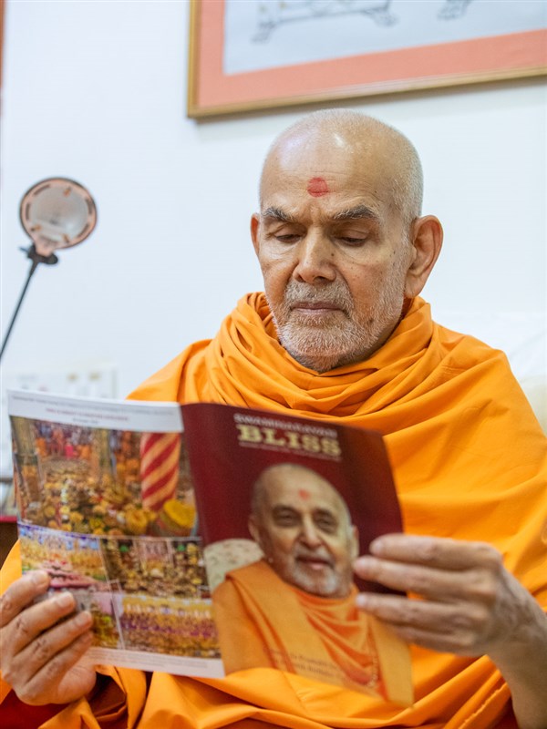 Swamishri reads the BAPS Sanstha's bimonthly English magazine, 'Swaminarayan Bliss'