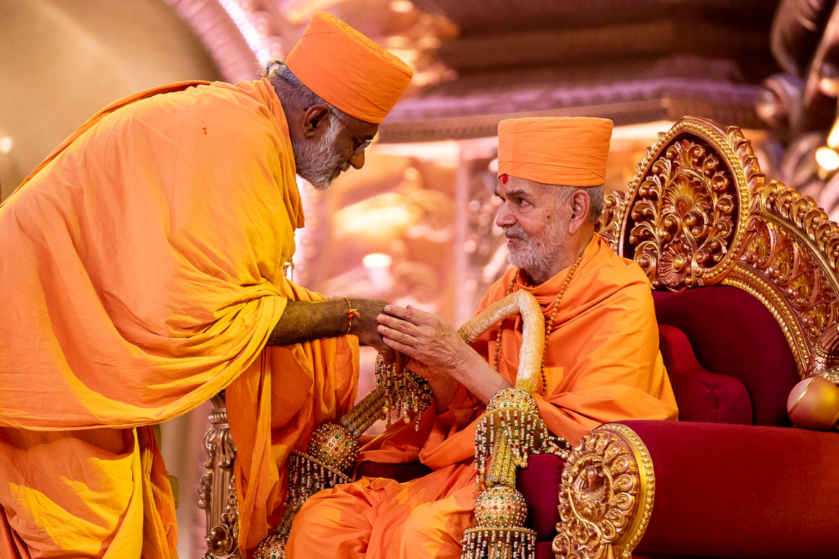 Abhayswarup Swami honors Swamishri with a garland