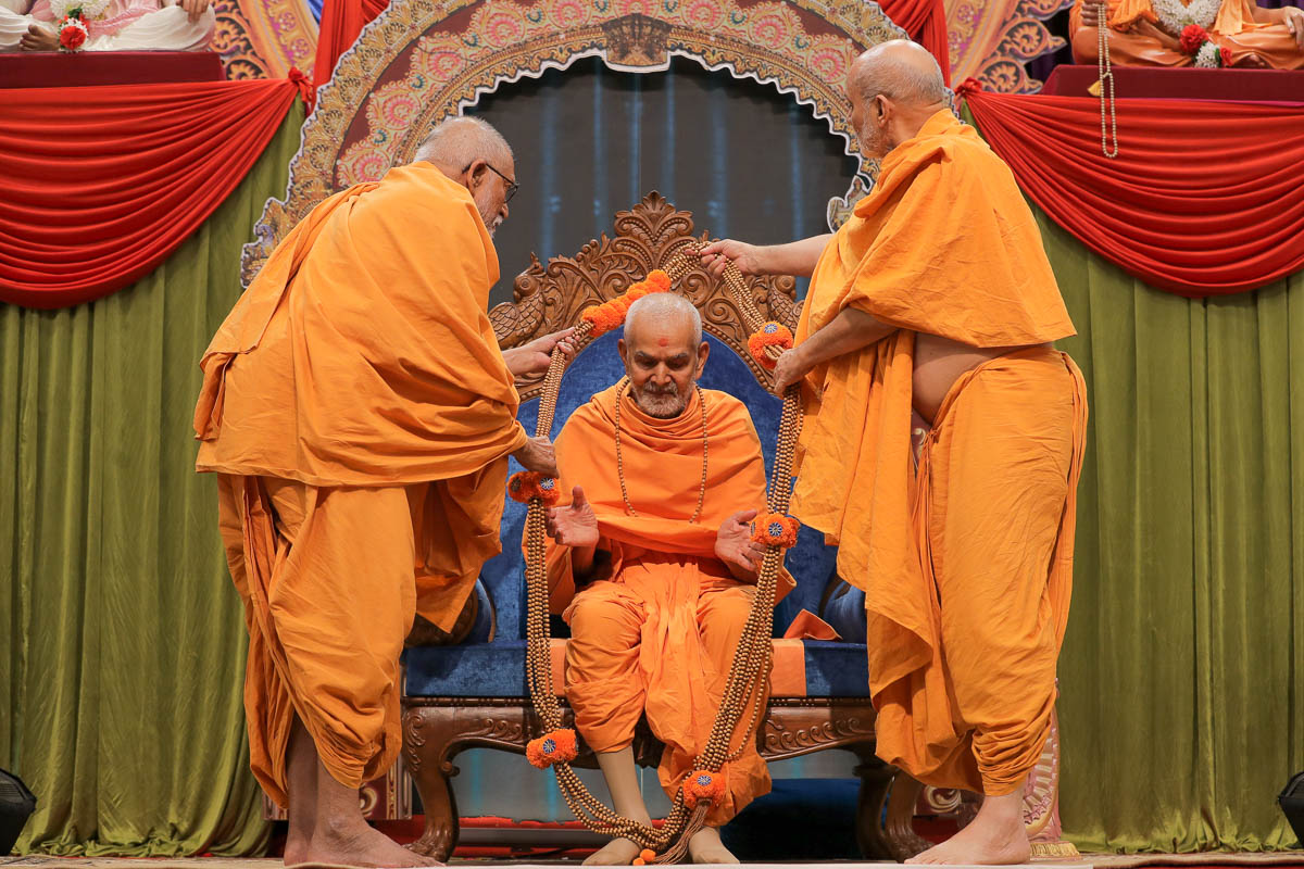 Pujya Kothari Swami and Pujya Viveksagar Swami honor Swamishri with a garland