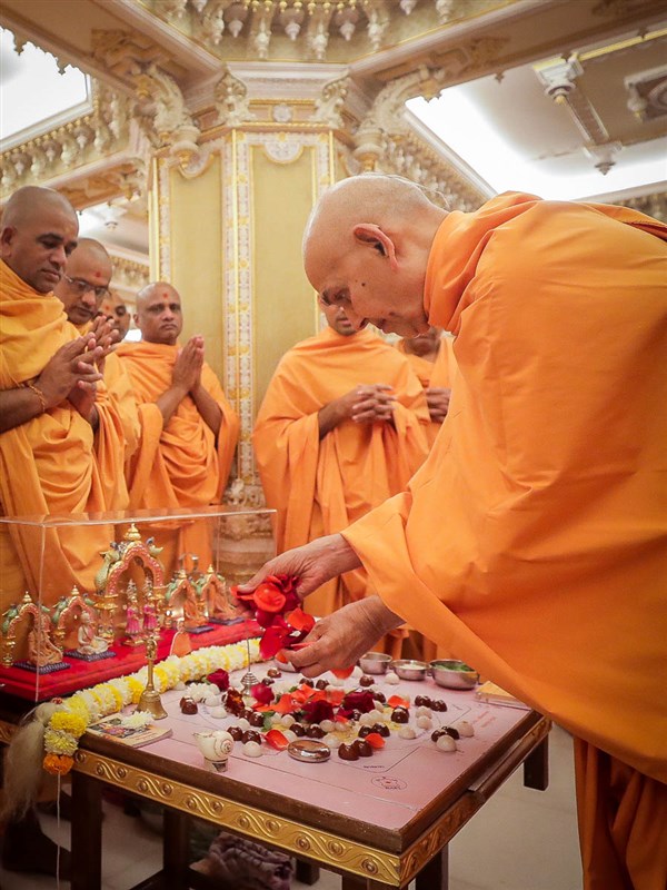 Swamishri offers flower petals in the mahapuja