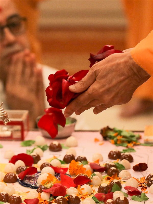 Swamishri showers flower petals in the mahapuja