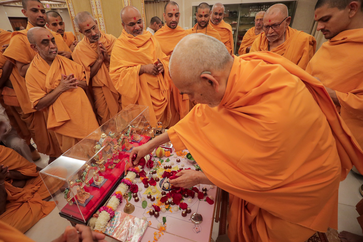 Swamishri offers flower petals in the mahapuja