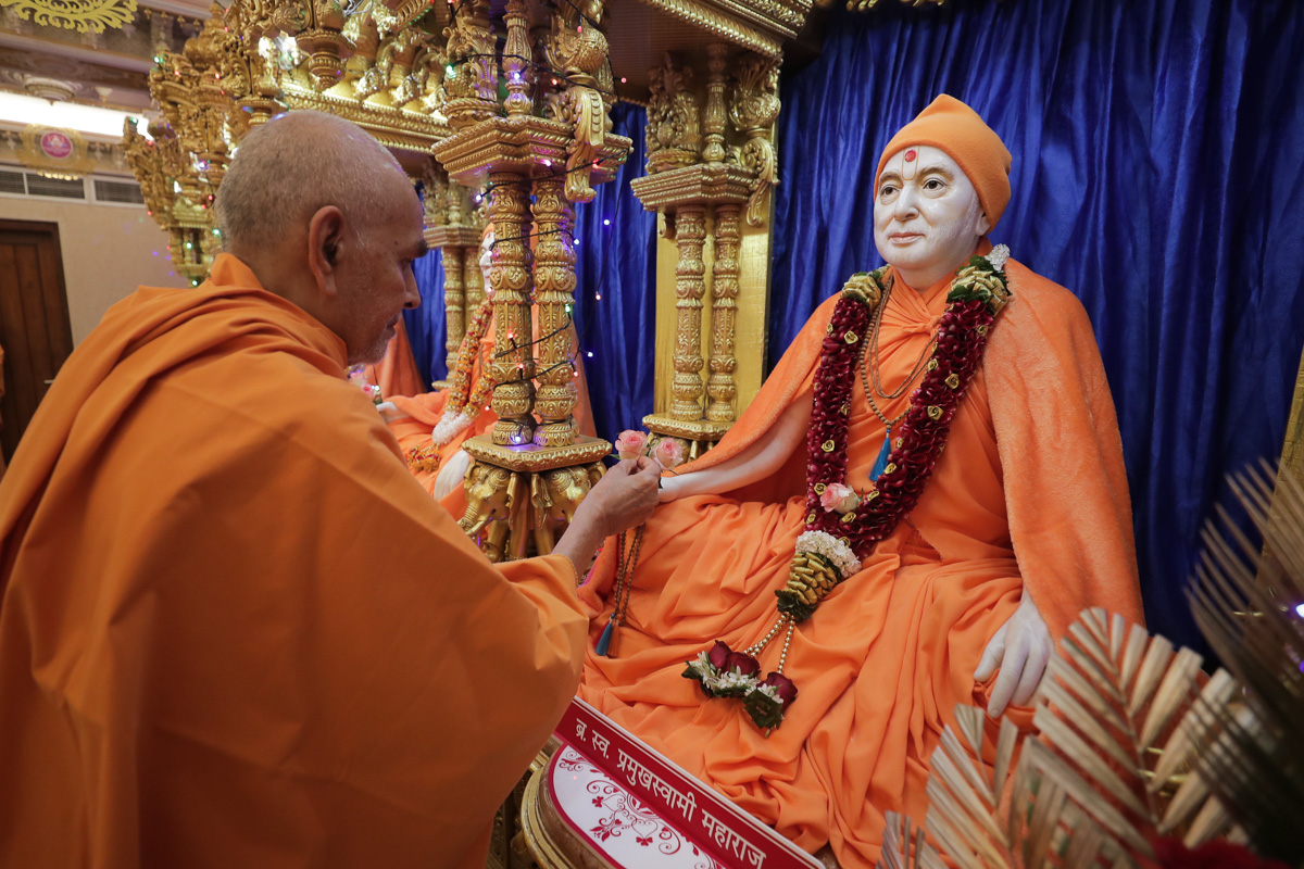 Swamishri adjusts mala offered to Brahmaswarup Pramukh Swami Maharaj