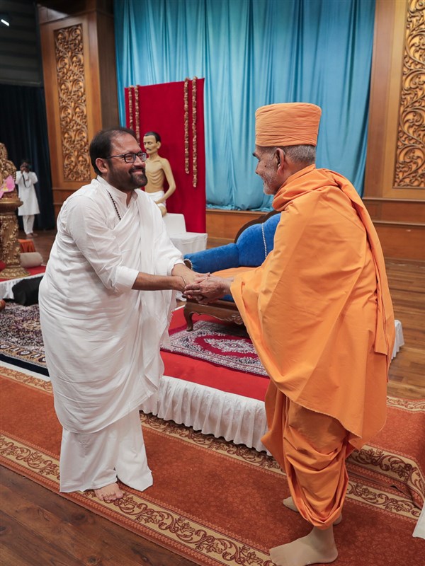 Pujya Gurudevshri Rakeshbhai welcomes Swamishri in the evening assembly organized by Shrimad Rajchandra Mission in the Yogi Hall