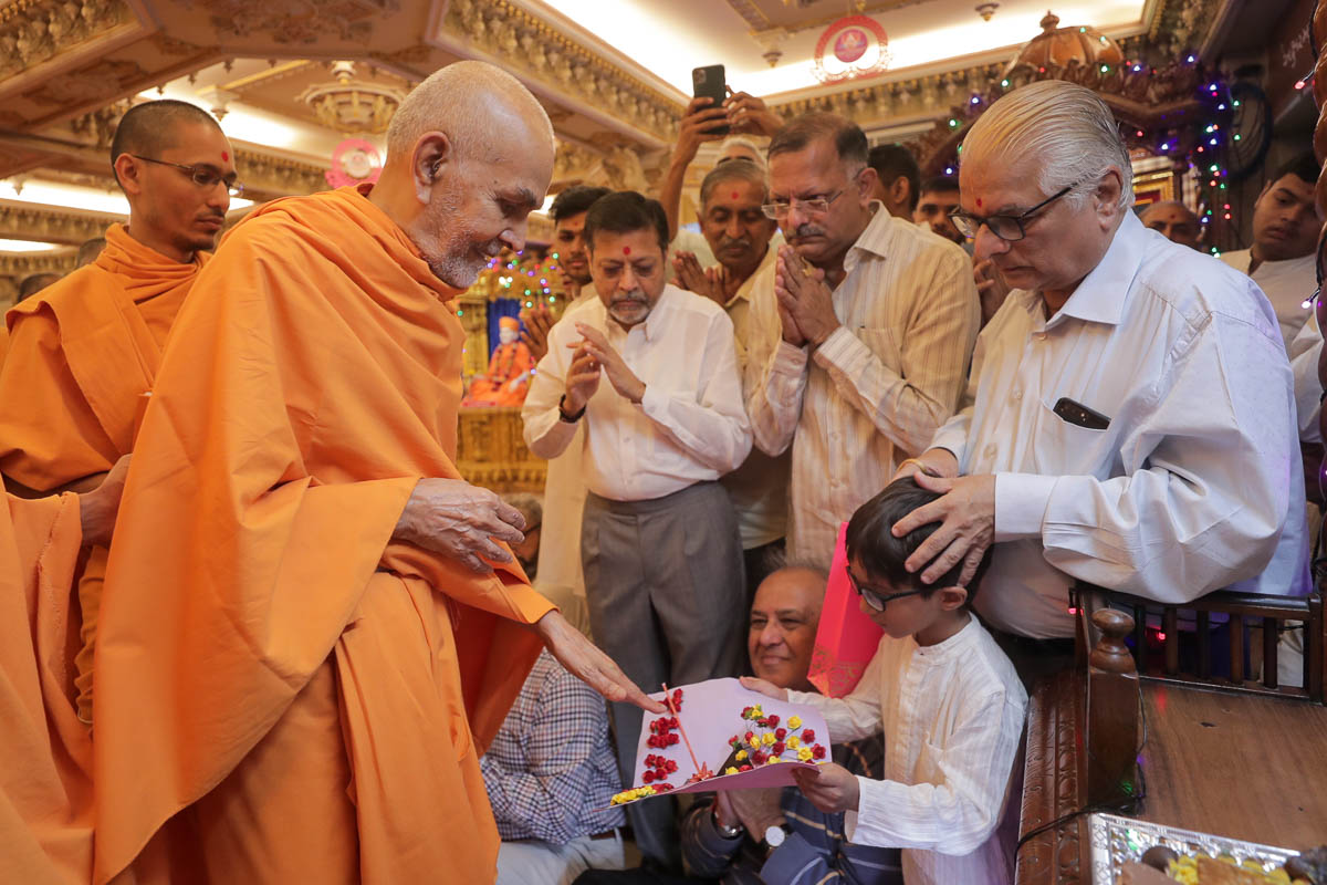 Swamishri sanctifies a decorative card made by a child