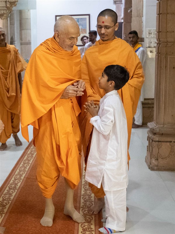 Swamishri interacts with a child 
