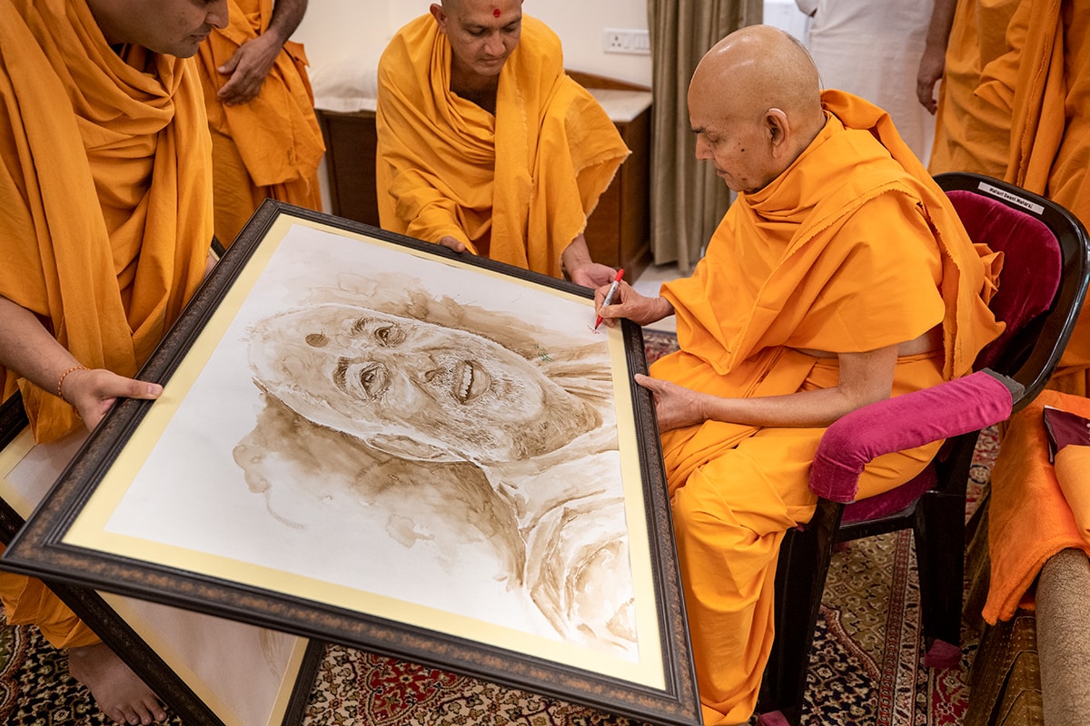 Swamishri sanctifies a painting of Brahmaswarup Pramukh Swami Maharaj