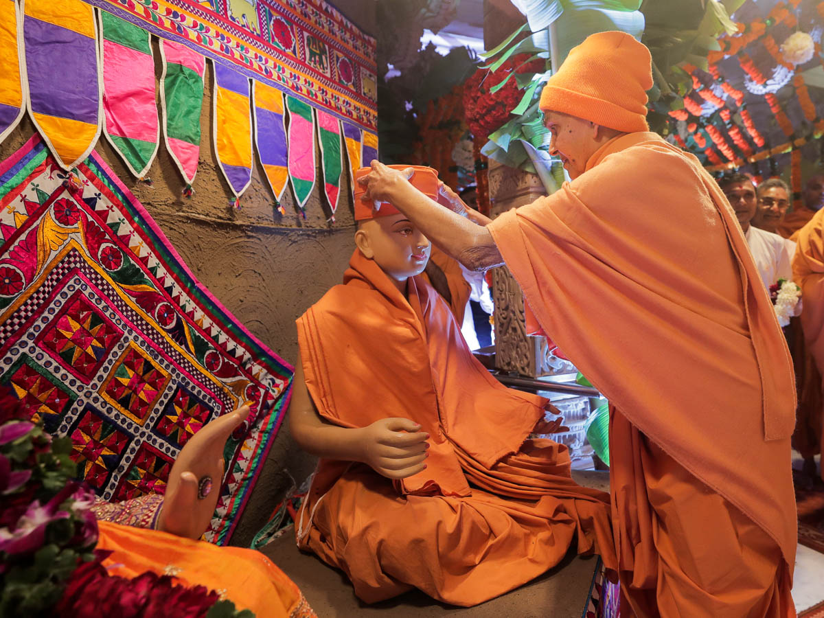 Swamishri places a pagh on the head of Aksharbrahman Gunatitanand Swami on Gunatit Diksha Din (Poshi Punam)