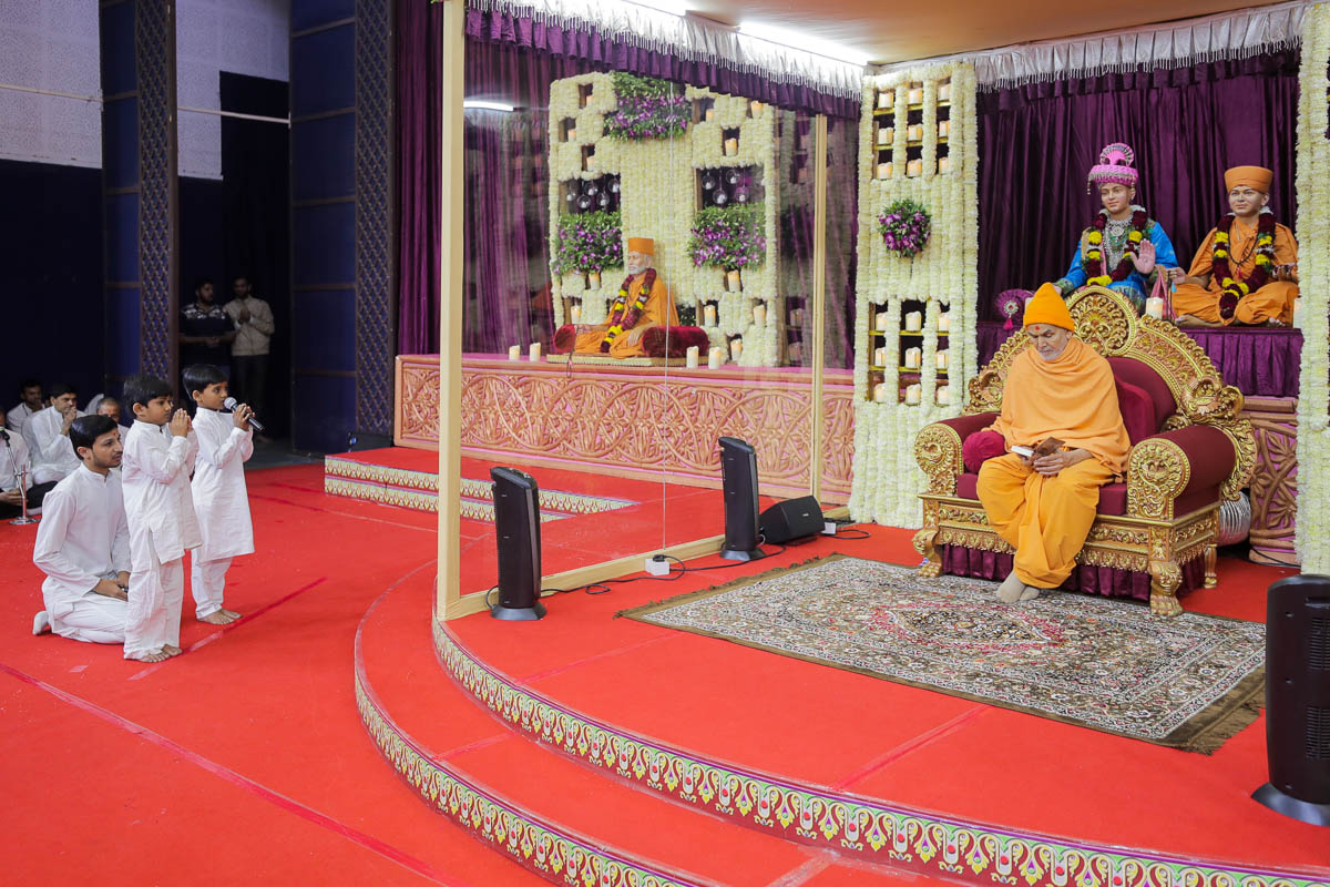 Children lead everyone in reciting the sadhana mantra and daily prayer in Swamishri's puja