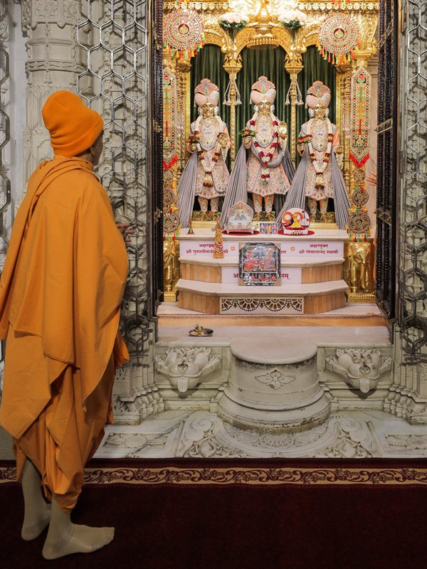 Swamishri engrossed in darshan of Bhagwan Swaminarayan, Aksharbrahman Gunatitanand Swami and Shri Gopalanand Swami