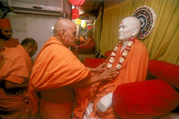  Swamishri arranges the garland of Shastriji Maharaj 