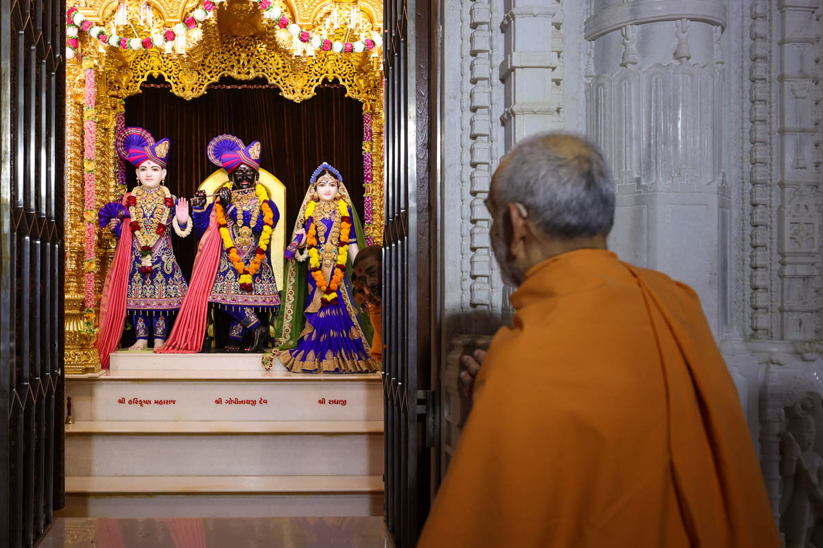 Swamishri engrossed in darshan of Shri Harikrishna Maharaj, Shri Gopinath Dev and Shri Radhikaji