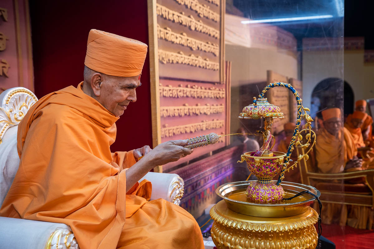 Swamishri sprays saffron-scented water on Shri Harikrishna Maharaj