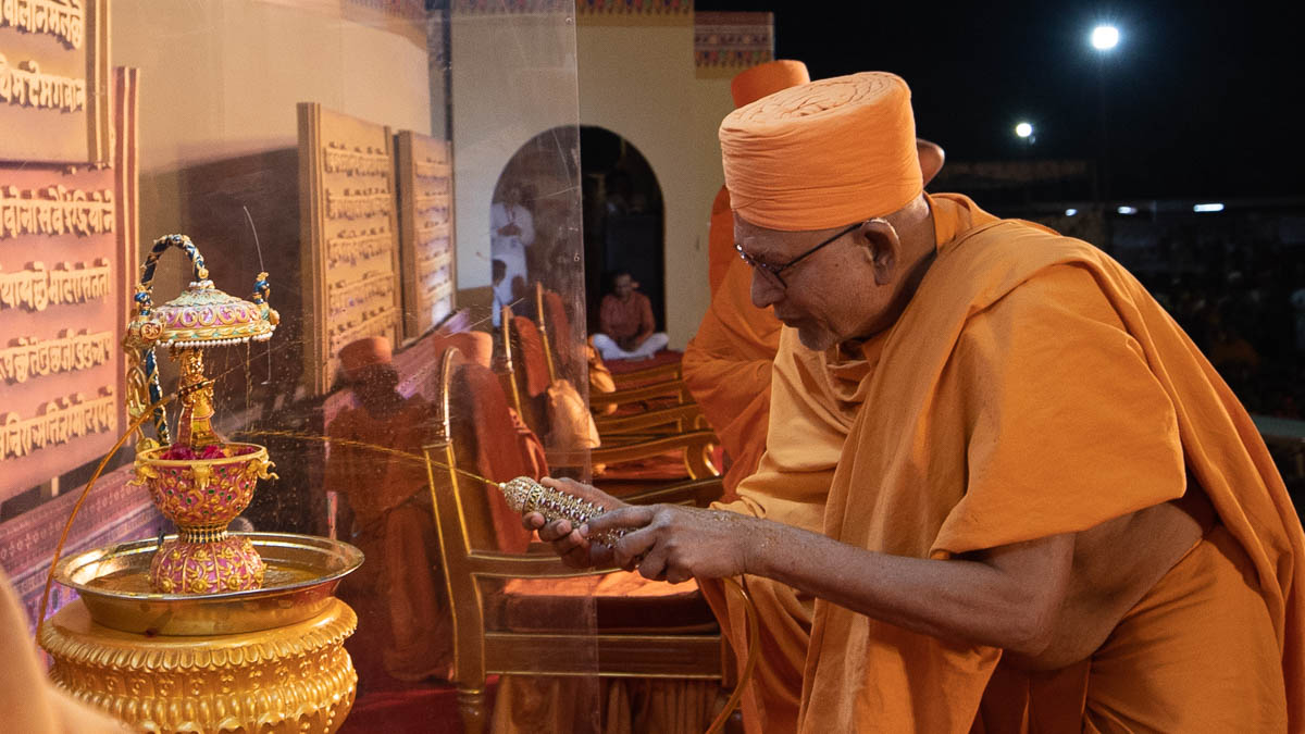 Pujya Kothari Swami sprays saffron-scented water on Shri Harikrishna Maharaj