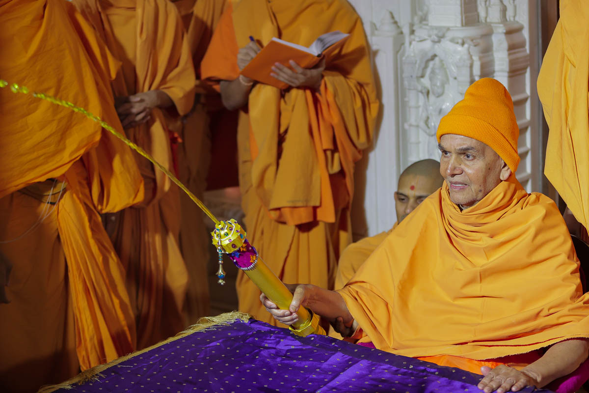 Swamishri sprays saffron-scented water on sadhus and sadhaks