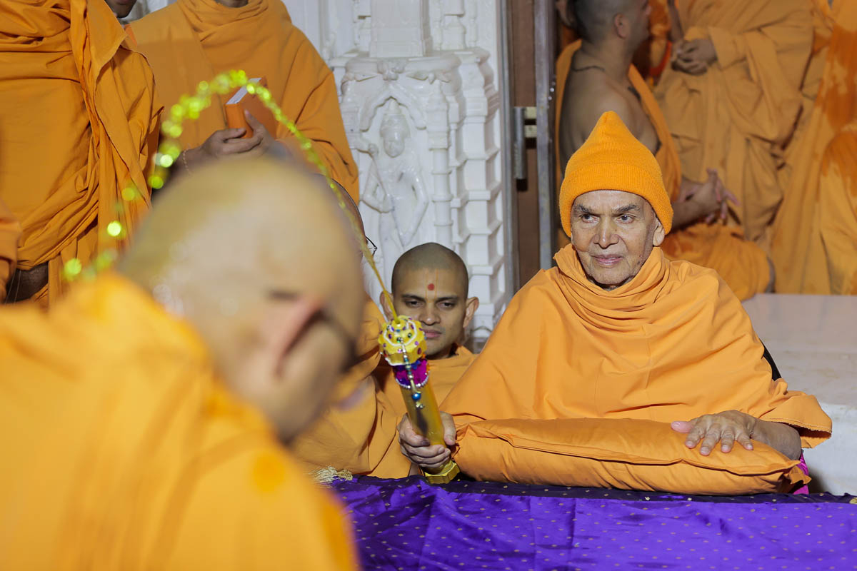 Swamishri sprays saffron-scented water on sadhus and sadhaks