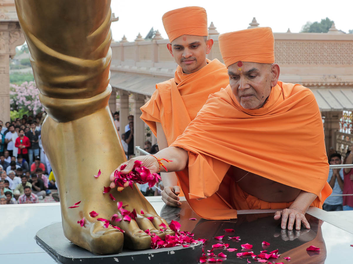 Swamishri offers flower petals at the feet of Bhaktaraj Shri Dada Khachar