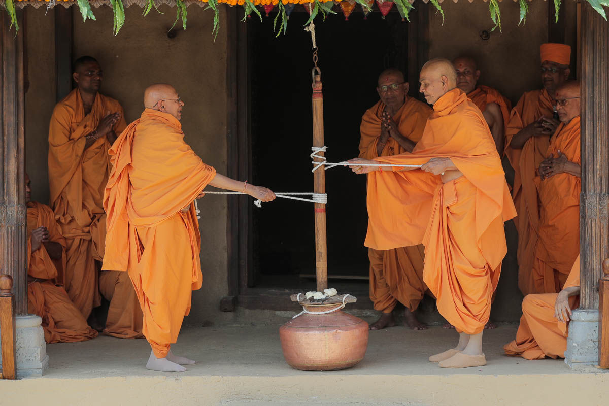 Swamishri and Pujya Tyagvallabh Swami churn yogurt in the same way that Bhagwan Swaminarayan had done in the darbar