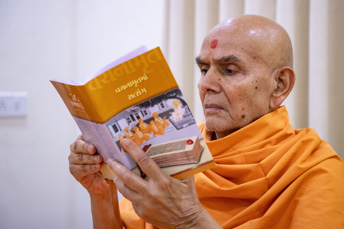 Swamishri reads a Vachanamrut Bicentenary publication: 'Vachahamrutma Satsang'