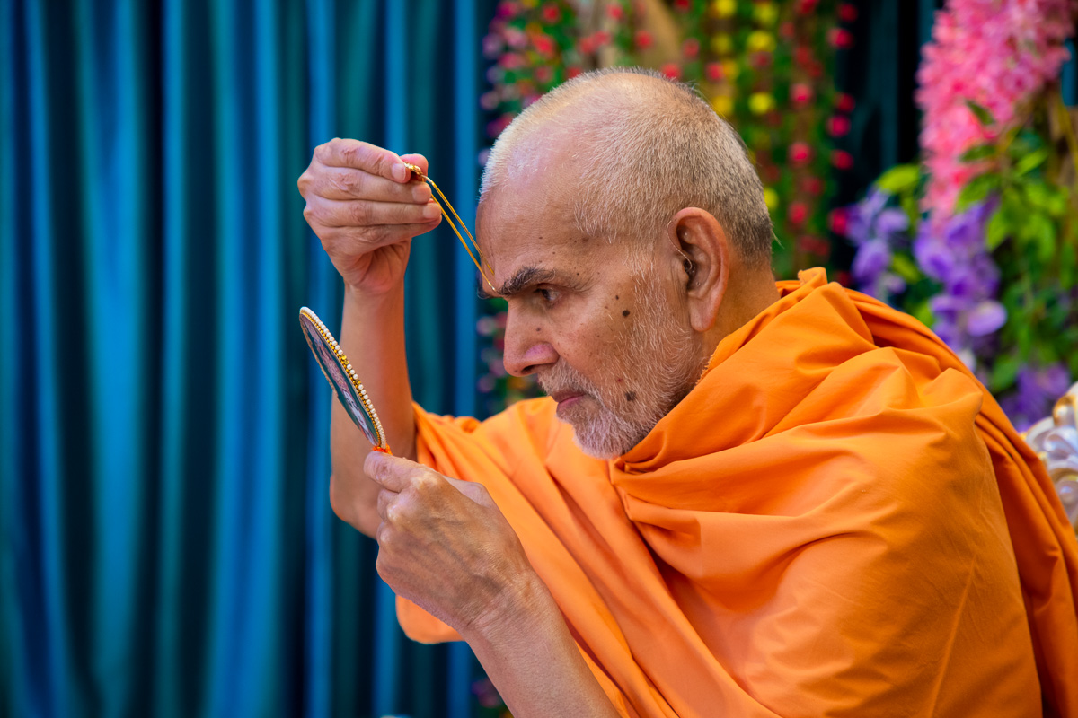 Swamishri applies tilak on his forehead 