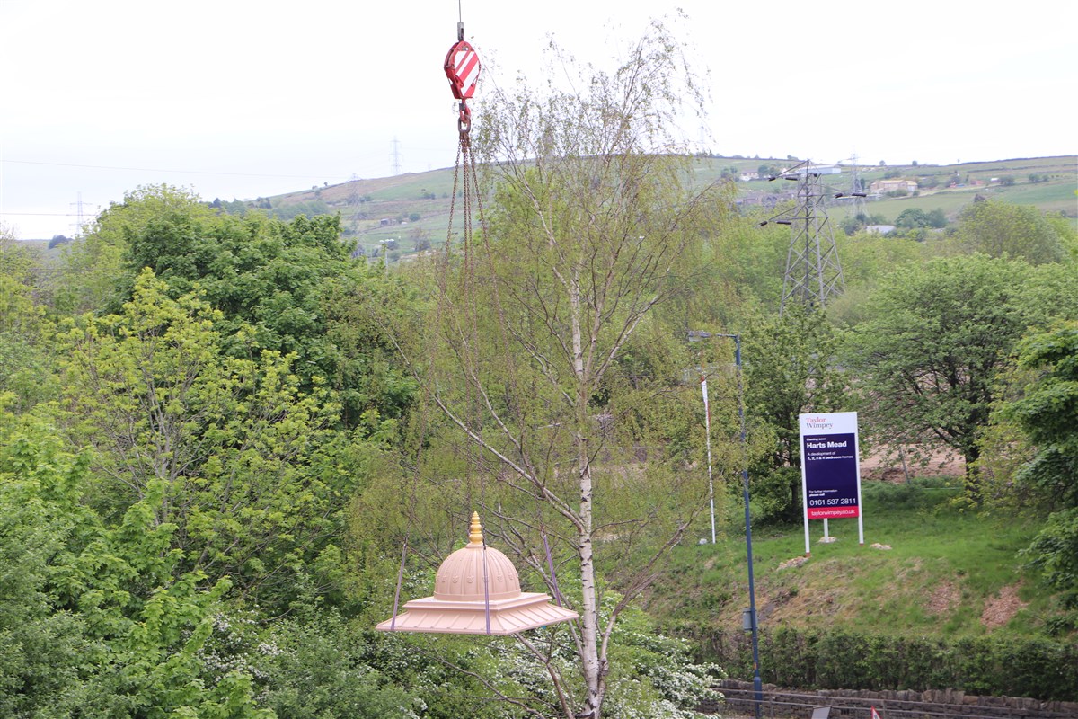 One of the chhatri tops is gently lowered into place
