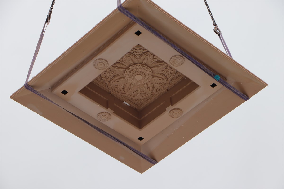 One of the chhatri tops is gently lowered into place