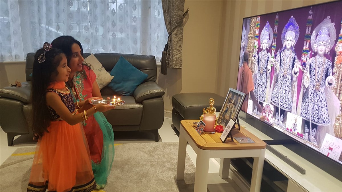 A young balika performs arti with her mother