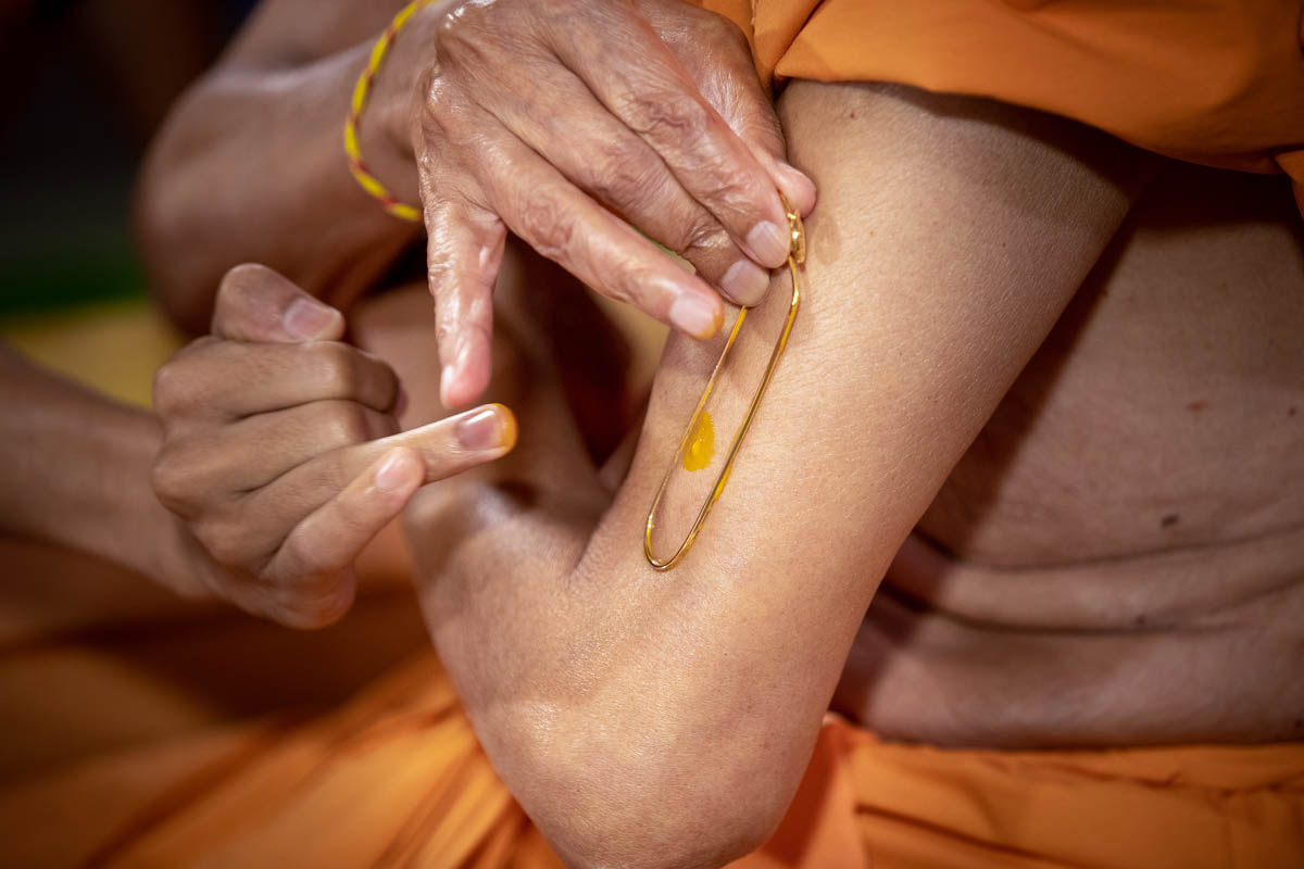Swamishri applies tilak on his upper arm