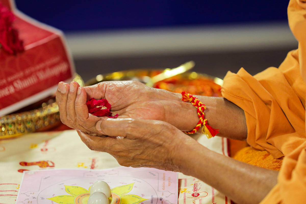 Swamishri held flower petals and rice grains as a part of the mahapuja rituals