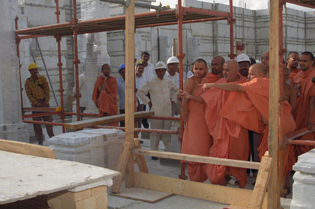 Senior swamis provide an update on the project to Pramukh Swami Maharaj during a site visit