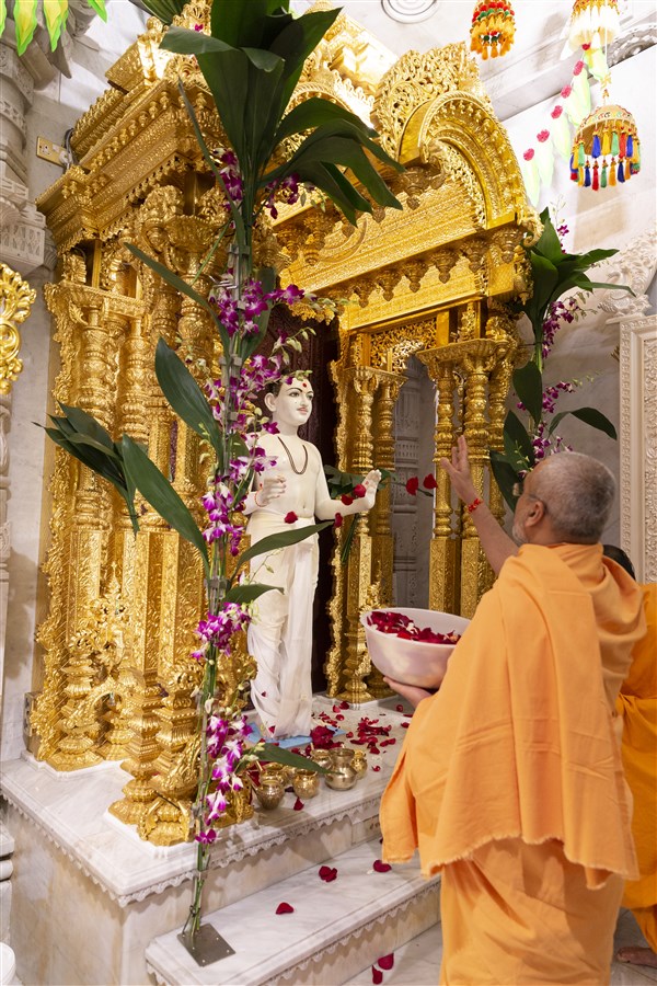 Prabuddhmuni Swami offers an abhishek of flower petals to Shri Ghanshyam Maharaj