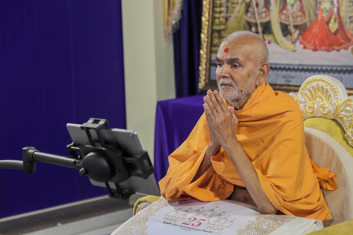 Mahant Swami Maharaj engrossed in the darshan of the murtis in London being offered abhishek remotely