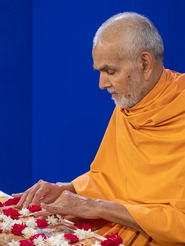 Swamishri adjusts murtis at the beginning of his daily puja