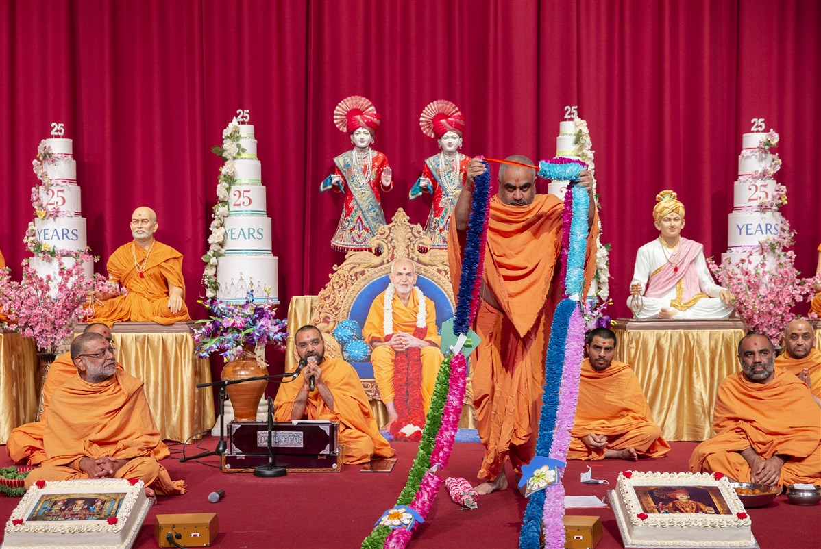 Yogvivekdas Swami honoured Swamishri with a long garland comprising prayers of devotees from UK & Europe who had started doing ghar sabha regularly