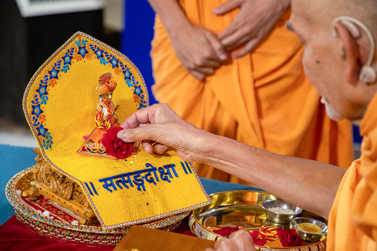 Swamishri offers a flower to Shri Harikrishna Maharaj