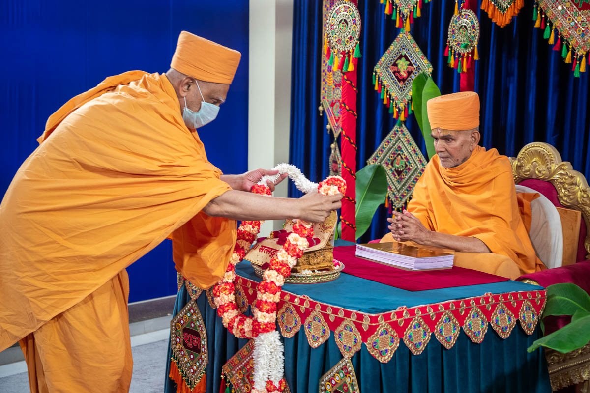 Atmaswarup Swami honors Shri Harikrishna Maharaj with a garland