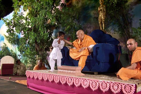  A child with Swamishri during the Children's Day program